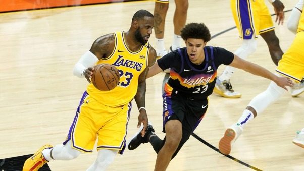 Los Angeles Lakers forward LeBron James, left, drives as Phoenix Suns forward Cameron Johnson defen...