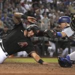 Arizona Diamondbacks' David Peralta, left, avoids the tag by Los Angeles Dodgers catcher Will Smith to score during the eighth inning of a baseball game Saturday, June 19, 2021, in Phoenix. (AP Photo/Rick Scuteri)