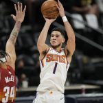 Phoenix Suns guard Devin Booker, right, shoots over Denver Nuggets center JaVale McGee in the first half of Game 4 of an NBA second-round playoff series Sunday, June 13, 2021, in Denver. (AP Photo/David Zalubowski)