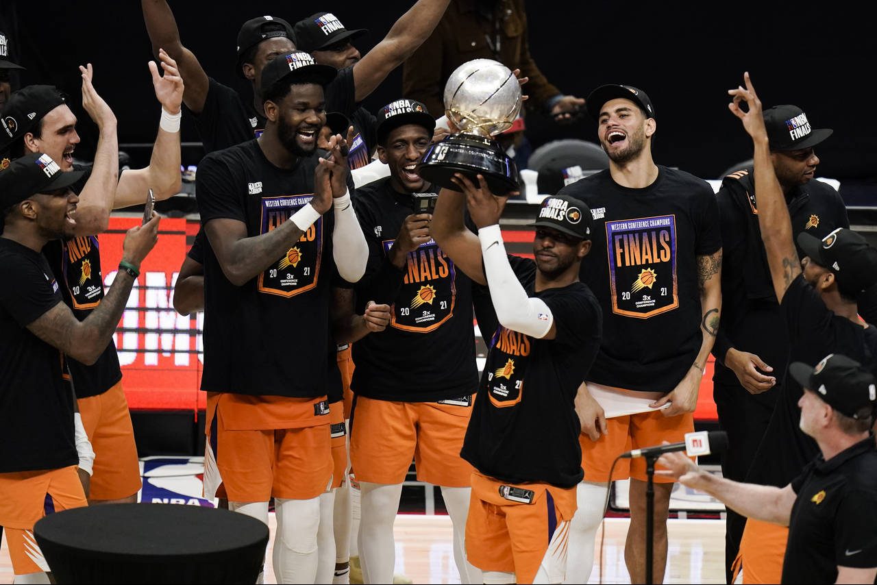 Phoenix Suns' Chris Paul hoists the trophy as he and his teammates celebrate after defeating the Lo...
