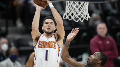Phoenix Suns guard Devin Booker, left, goes up for a basket as Denver Nuggets forward Will Barton d...