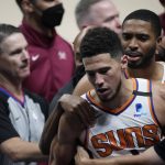 Phoenix Suns guard Devin Booker is restrained after getting into an argument with Denver Nuggets center Nikola Jokic in the second half of Game 4 of an NBA second-round playoff series Sunday, June 13, 2021, in Denver. (AP Photo/David Zalubowski)
