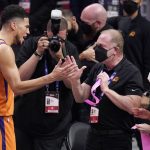 Phoenix Suns' Devin Booker, left, celebrates with Suns owner Robert Sarver, center, as time runs out in Game 6 of the NBA basketball Western Conference Finals against the Los Angeles Clippers Wednesday, June 30, 2021, in Los Angeles. The Suns won the game 130-103 to take the series 4-2. (AP Photo/Mark J. Terrill)