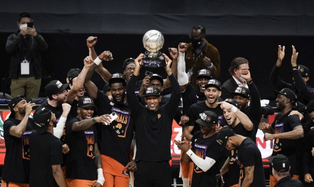 Phoenix Suns head coach Monty Williams, center, hoists the trophy as he and his players celebrate a...