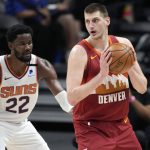 Denver Nuggets center Nikola Jokic, right, looks to pass the ball as Phoenix Suns center Deandre Ayton defends in the first half of Game 4 of an NBA second-round playoff series Sunday, June 13, 2021, in Denver. (AP Photo/David Zalubowski)