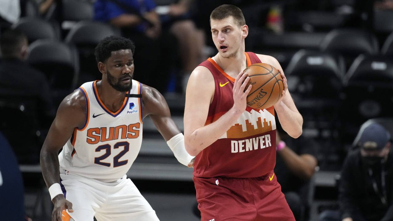Denver Nuggets center Nikola Jokic, right, looks to pass the ball as Phoenix Suns center Deandre Ay...