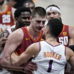 Referee David Guthrie, right, struggles to keep Denver Nuggets center Nikola Jokic, back, from fighting with Phoenix Suns guard Devin Booker in the second half of Game 4 of an NBA second-round playoff series Sunday, June 13, 2021, in Denver. (AP Photo/David Zalubowski)