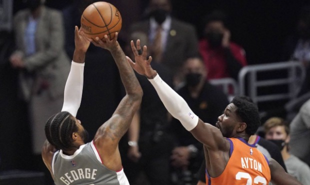 Los Angeles Clippers guard Paul George, left, shoots as Phoenix Suns center Deandre Ayton defends d...