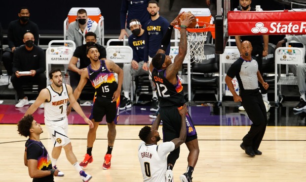 Torrey Craig #12 of the Phoenix Suns slam dunks the ball over JaMychal Green #0 of the Denver Nugge...