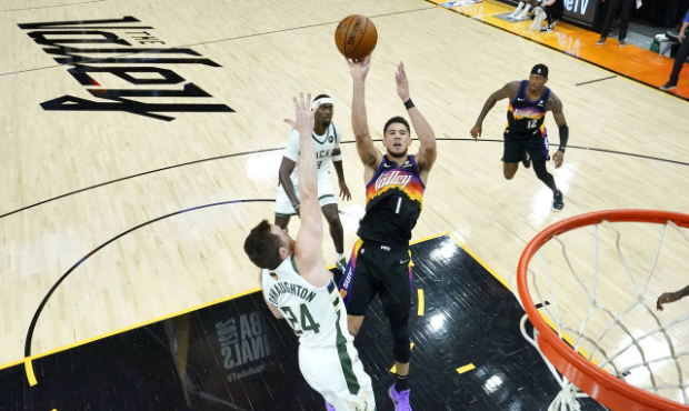 Phoenix Suns guard Devin Booker (1) shoots over Milwaukee Bucks guard Pat Connaughton (24) during t...