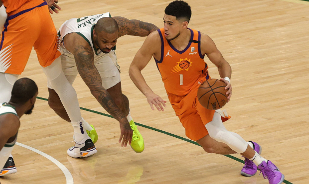 Devin Booker #1 of the Phoenix Suns drives against P.J. Tucker #17 of the Milwaukee Bucks during th...