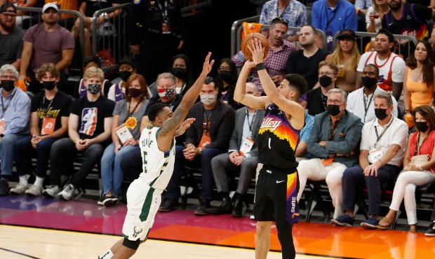 Devin Booker #1 of the Phoenix Suns shoots against Jeff Teague #5 of the Milwaukee Bucks during the...
