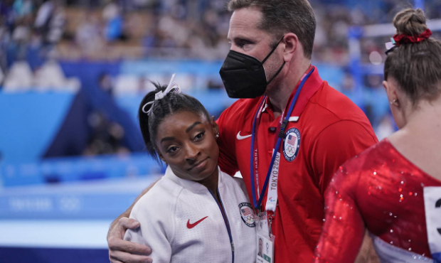 Coach Laurent Landi embraces Simone Biles, after she exited the team final with apparent injury, at...