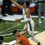 Milwaukee Bucks forward Giannis Antetokounmpo drives to the basket over Phoenix Suns guard Devin Booker (1) during the first half of Game 4 of basketball's NBA Finals in Milwaukee, Wednesday, July 14, 2021. (AP Photo/Paul Sancya)