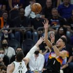 Phoenix Suns guard Devin Booker (1) shoots over Milwaukee Bucks center Brook Lopez, left, during the first half of Game 1 of basketball's NBA Finals, Tuesday, July 6, 2021, in Phoenix. (AP Photo/Ross D. Franklin)