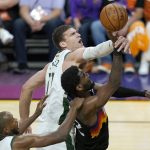 Phoenix Suns center Deandre Ayton, middle, is defended by Milwaukee Bucks center Brook Lopez, top, and forward Khris Middleton during the second half of Game 2 of basketball's NBA Finals, Thursday, July 8, 2021, in Phoenix. (AP Photo/Ross D. Franklin)