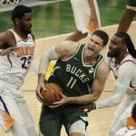 Milwaukee Bucks' Brook Lopez (11) is fouled as he drives between Phoenix Suns' Jae Crowder (99) and Deandre Ayton (22) during the second half of Game 3 of basketball's NBA Finals, Sunday, July 11, 2021, in Milwaukee. (AP Photo/Aaron Gash)