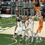 Phoenix Suns guard Devin Booker, right, shoots over Milwaukee Bucks guard Jeff Teague (5) and guard Pat Connaughton (24) during the second half of Game 4 of basketball's NBA Finals in Milwaukee, Wednesday, July 14, 2021. (AP Photo/Paul Sancya)