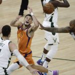 Phoenix Suns guard Devin Booker (1) loses the ball between Milwaukee Bucks center Brook Lopez (11) and forward P.J. Tucker, right, during the first half of Game 4 of basketball's NBA Finals Wednesday, July 14, 2021, in Milwaukee. (AP Photo/Aaron Gash)