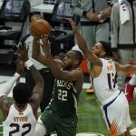 Milwaukee Bucks' Khris Middleton (22) shoots against Phoenix Suns' Cameron Payne (15) during the first half of Game 3 of basketball's NBA Finals in Milwaukee, Sunday, July 11, 2021. (AP Photo/Paul Sancya)