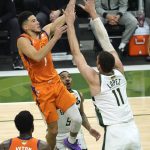 Phoenix Suns guard Devin Booker (1) drives to the basket over Milwaukee Bucks center Brook Lopez (11) during the first half of Game 4 of basketball's NBA Finals in Milwaukee, Wednesday, July 14, 2021. (AP Photo/Paul Sancya)