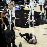Phoenix Suns guard Chris Paul lies on the court after being fouled by Milwaukee Bucks center Brook Lopez, left, as forward Mikal Bridges (25) looks on during the second half of Game 1 of basketball's NBA Finals, Tuesday, July 6, 2021, in Phoenix. (AP Photo/Matt York)
