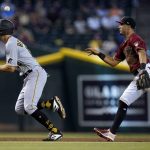 Arizona Diamondbacks second baseman Josh Rojas, right, tosses the ball over the head of Pittsburgh Pirates' Bryan Reynolds, left, during a rundown in the fifth inning of a baseball game, Wednesday, July 21, 2021, in Phoenix. Pirates' Reynolds was tagged out at third base. (AP Photo/Ross D. Franklin)