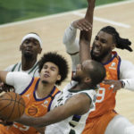 Phoenix Suns forward Jae Crowder, right, blocks a shot by Milwaukee Bucks forward Khris Middleton, center, during the second half of Game 4 of basketball's NBA Finals Wednesday, July 14, 2021, in Milwaukee. (AP Photo/Aaron Gash)