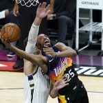Phoenix Suns forward Mikal Bridges (25) shoots under Milwaukee Bucks center Brook Lopez during the first half of Game 1 of basketball's NBA Finals, Tuesday, July 6, 2021, in Phoenix. (AP Photo/Matt York)