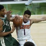 Milwaukee Bucks forward Giannis Antetokounmpo (34) and Phoenix Suns guard Devin Booker (1) battle for a loose ball during the second half of Game 3 of basketball's NBA Finals in Milwaukee, Sunday, July 11, 2021. (AP Photo/Paul Sancya)