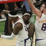 Milwaukee Bucks' Jrue Holiday, middle, drives to the basket between Phoenix Suns' Torrey Craig, left, and Frank Kaminsky, right, during the second half of Game 3 of basketball's NBA Finals, Sunday, July 11, 2021, in Milwaukee. (AP Photo/Aaron Gash)