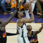 Milwaukee Bucks forward Giannis Antetokounmpo, middle, shoots between Phoenix Suns center Deandre Ayton (22) and guard Cameron Payne during the first half of Game 5 of basketball's NBA Finals, Saturday, July 17, 2021, in Phoenix. (AP Photo/Ross D. Franklin)