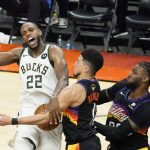 Milwaukee Bucks forward Khris Middleton (22) is defended by Phoenix Suns guard Devin Booker, middle, and forward Jae Crowder during the second half of Game 5 of basketball's NBA Finals, Saturday, July 17, 2021, in Phoenix. (AP Photo/Matt York)