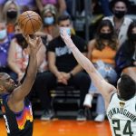 Phoenix Suns guard Chris Paul, left, shoots a 3-pointer over Milwaukee Bucks guard Pat Connaughton (24) during the second half of Game 1 of basketball's NBA Finals, Tuesday, July 6, 2021, in Phoenix. The Suns defeated the Bucks 118-105. (AP Photo/Ross D. Franklin)