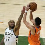 Milwaukee Bucks forward P.J. Tucker (17) tries to block a shot by Phoenix Suns guard Devin Booker (1) during the second half of Game 4 of basketball's NBA Finals in Milwaukee, Wednesday, July 14, 2021. (AP Photo/Paul Sancya)