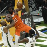 Phoenix Suns center Deandre Ayton (22) grabs a rebound over Milwaukee Bucks forward P.J. Tucker, left, and guard Jrue Holiday, right, during the first half of Game 4 of basketball's NBA Finals in Milwaukee, Wednesday, July 14, 2021. (AP Photo/Paul Sancya)