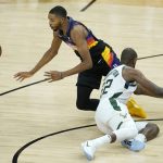 Phoenix Suns forward Mikal Bridges, left, reaches for the ball against Milwaukee Bucks forward Khris Middleton during the first half of Game 2 of basketball's NBA Finals, Thursday, July 8, 2021, in Phoenix. (AP Photo/Ross D. Franklin)