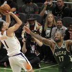 Phoenix Suns' Devin Booker (1) shoots against Milwaukee Bucks' P.J. Tucker (17) during the second half of Game 3 of basketball's NBA Finals, Sunday, July 11, 2021, in Milwaukee. (AP Photo/Aaron Gash)