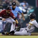 Arizona Diamondbacks shortstop Nick Ahmed, left, tags out Pittsburgh Pirates' Bryan Reynolds (10) attempting to steal third base as umpire Nestor Ceja watches during the fifth inning of a baseball game Wednesday, July 21, 2021, in Phoenix. (AP Photo/Ross D. Franklin)