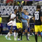 
              Jamaica forward Cory Burke (9) is issued a yellow card by referee Cesar Ramos, right center, as Daniel Johnson (16) and Bobby Reid (10) look on in the first half of a CONCACAF Gold Cup quarterfinals soccer match, Sunday, July 25, 2021, in Arlington, Texas. Burke received the card for knocking down United States midfielder Gianluca Busio during play. (AP Photo/Brandon Wade)
            