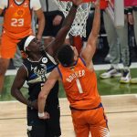 Milwaukee Bucks guard Jrue Holiday challenges Phoenix Suns guard Devin Booker (1) as he drives to the basket during the first half of Game 6 of basketball's NBA Finals in Milwaukee, Tuesday, July 20, 2021. (AP Photo/Paul Sancya)