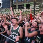 Fans watch television coverage of Game 6 of the NBA basketball finals between the Milwaukee Bucks and the Phoenix Suns, Tuesday, July 20, 2021, in Milwaukee. (AP Photo/Jeffrey Phelps)