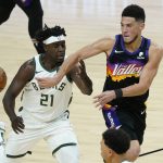 Phoenix Suns guard Devin Booker (1) dishes off around Milwaukee Bucks guard Jrue Holiday (21) during the first half of Game 1 of basketball's NBA Finals, Tuesday, July 6, 2021, in Phoenix. (AP Photo/Matt York)