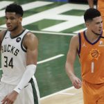 Milwaukee Bucks forward Giannis Antetokounmpo (34) celebrates in front of Phoenix Suns guard Devin Booker (1) at the end of Game 4 of basketball's NBA Finals Wednesday, July 14, 2021, in Milwaukee. (AP Photo/Aaron Gash)