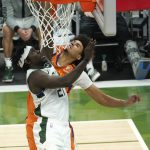 Phoenix Suns forward Cameron Johnson, right, blocks a shot by Milwaukee Bucks guard Jrue Holiday during the second half of Game 4 of basketball's NBA Finals in Milwaukee, Wednesday, July 14, 2021. (AP Photo/Paul Sancya)