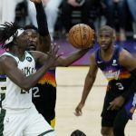 Milwaukee Bucks guard Jrue Holiday, left, drives past Phoenix Suns center Deandre Ayton, back left, and Suns guard Chris Paul (3) during the first half of Game 1 of basketball's NBA Finals, Tuesday, July 6, 2021, in Phoenix. (AP Photo/Ross D. Franklin)