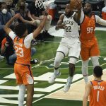 Milwaukee Bucks forward Khris Middleton (22) drives to the basket between Phoenix Suns forward Cameron Johnson (23), forward Jae Crowder (99) and guard Devin Booker (1) during the first half of Game 4 of basketball's NBA Finals in Milwaukee, Wednesday, July 14, 2021. (AP Photo/Paul Sancya)