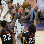 Milwaukee Bucks guard Jrue Holiday, middle, shoots against Phoenix Suns center Deandre Ayton (22) and forward Cameron Johnson (23) during the first half of Game 5 of basketball's NBA Finals, Saturday, July 17, 2021, in Phoenix. (AP Photo/Ross D. Franklin)