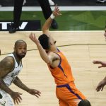 Phoenix Suns guard Devin Booker, center, fights for a loose ball with Milwaukee Bucks forward P.J. Tucker, left, and center Brook Lopez, right, during the first half of Game 4 of basketball's NBA Finals in Milwaukee, Wednesday, July 14, 2021. (AP Photo/Paul Sancya)