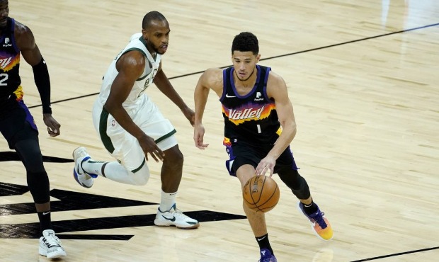 Phoenix Suns guard Devin Booker (1) drives as Milwaukee Bucks forward Khris Middleton defends durin...